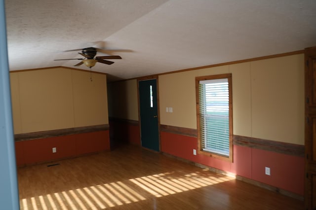 unfurnished room with a textured ceiling, vaulted ceiling, ceiling fan, crown molding, and wood-type flooring