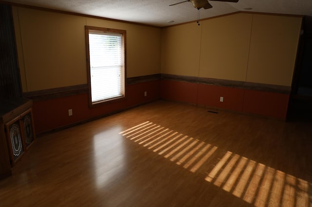 unfurnished room featuring ceiling fan, crown molding, lofted ceiling, a textured ceiling, and light wood-type flooring