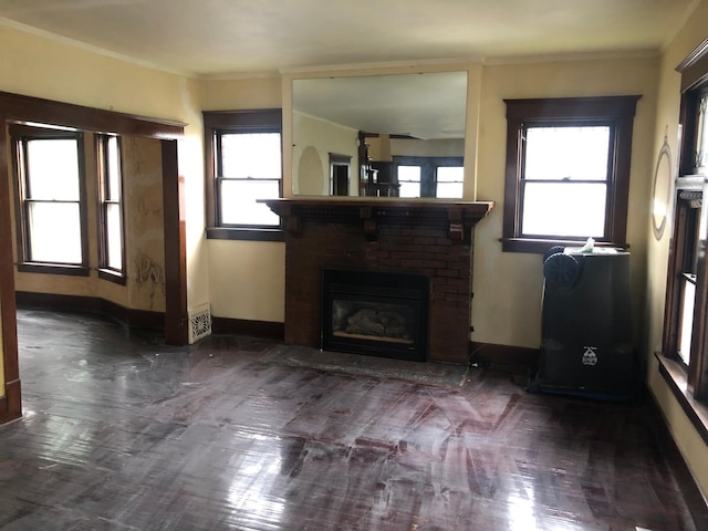 unfurnished living room featuring crown molding, plenty of natural light, and a brick fireplace