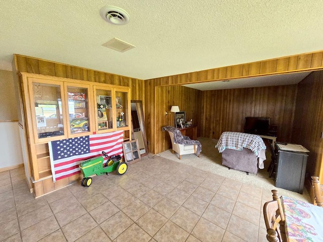 sitting room with tile patterned floors, a textured ceiling, and wooden walls