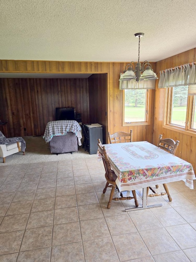 unfurnished dining area featuring tile patterned floors, wood walls, and a notable chandelier