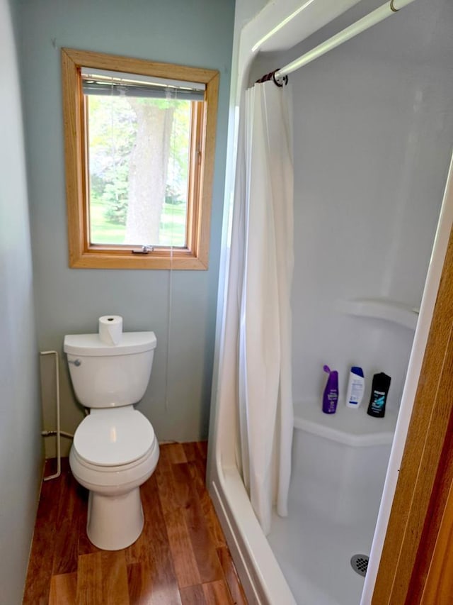 bathroom featuring a shower with shower curtain, hardwood / wood-style flooring, and toilet