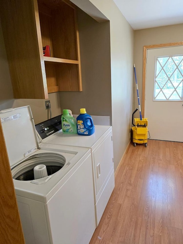 laundry area with light hardwood / wood-style flooring and washer and clothes dryer