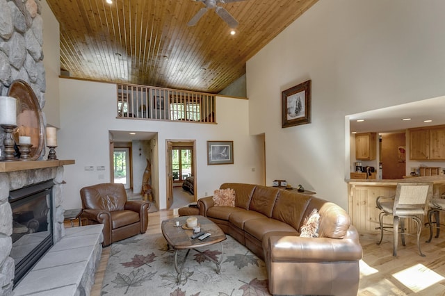 living room with a fireplace, a towering ceiling, ceiling fan, and wood ceiling