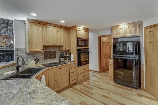 kitchen featuring black appliances, sink, decorative backsplash, light brown cabinetry, and light hardwood / wood-style floors