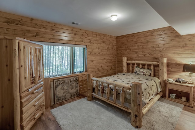 bedroom with light wood-type flooring and wooden walls