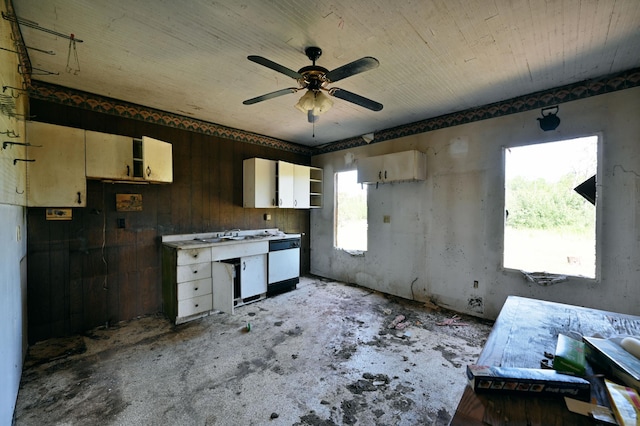 kitchen featuring ceiling fan, white dishwasher, and wooden walls