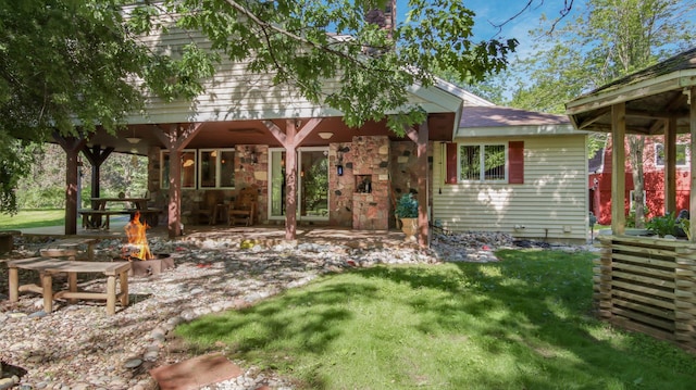 rear view of house with a yard and a fire pit