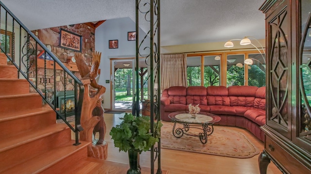 living room with wood-type flooring, lofted ceiling, and a textured ceiling