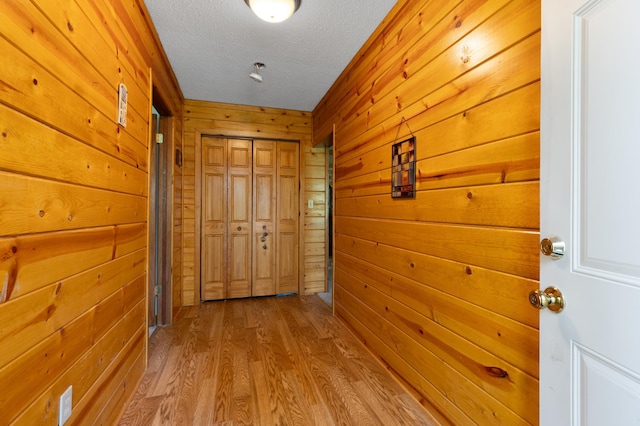 corridor featuring a textured ceiling, wooden walls, and hardwood / wood-style floors