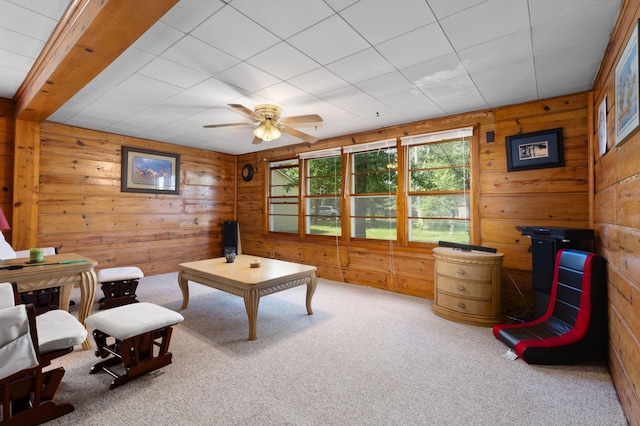 living room with carpet flooring, ceiling fan, and wood walls