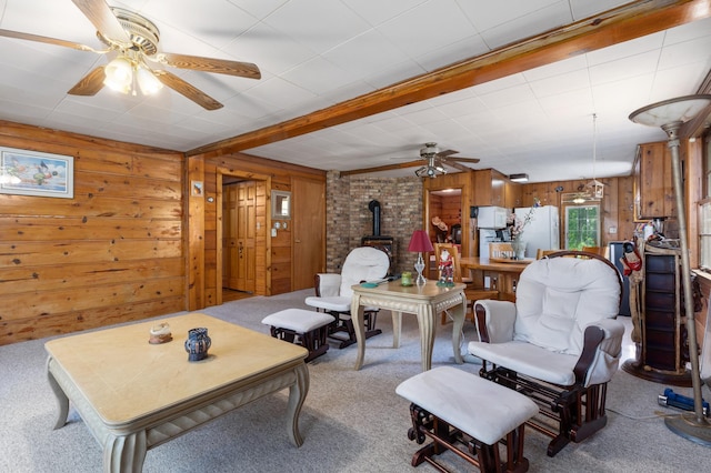 living room with brick wall, wooden walls, a wood stove, carpet, and ceiling fan