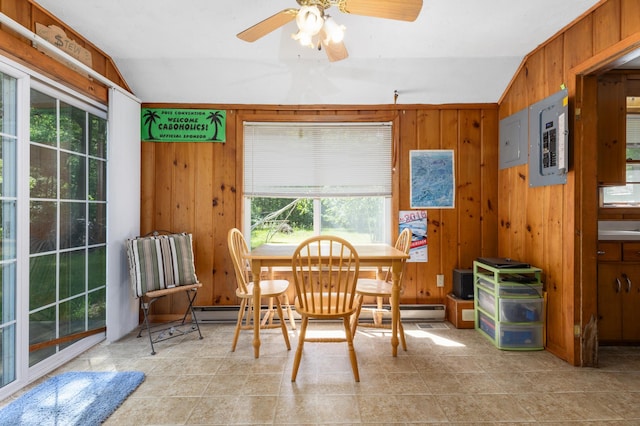 dining space with wood walls, ceiling fan, light tile floors, and lofted ceiling