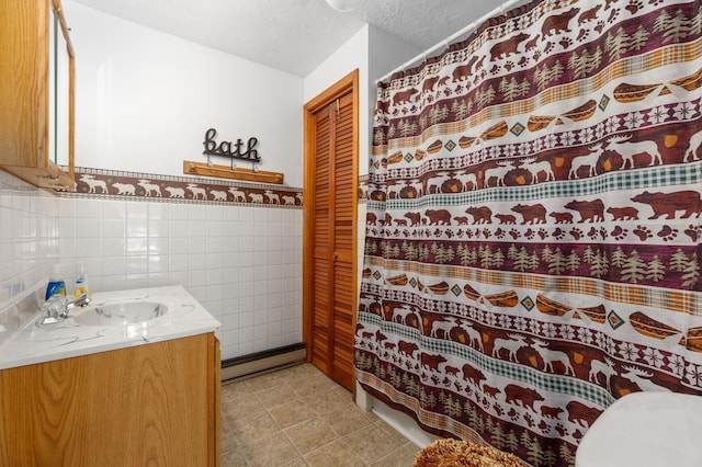 bathroom with vanity with extensive cabinet space, tile walls, a textured ceiling, tile floors, and toilet