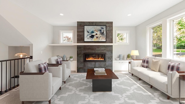 living room featuring plenty of natural light, a tiled fireplace, and light carpet