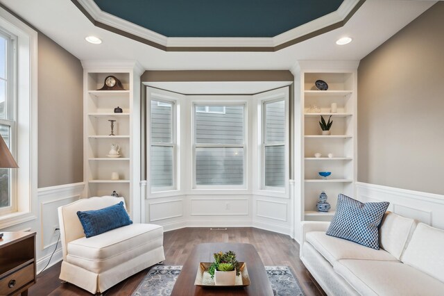 sitting room featuring built in shelves, crown molding, and dark hardwood / wood-style flooring