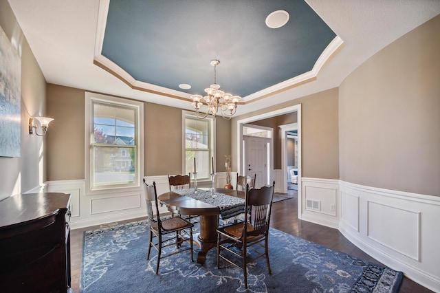 dining room with an inviting chandelier, a tray ceiling, crown molding, and dark wood-type flooring