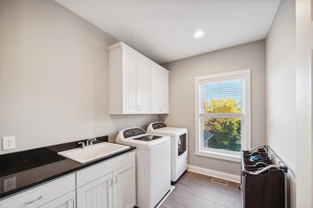 clothes washing area with cabinets, independent washer and dryer, dark hardwood / wood-style floors, and sink