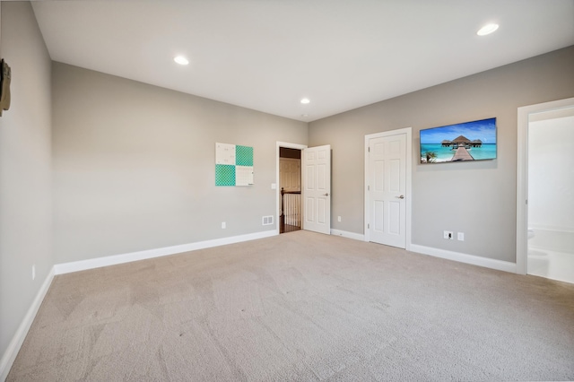 unfurnished bedroom featuring connected bathroom and light colored carpet