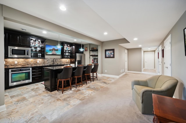 bar with pendant lighting, sink, stainless steel appliances, light colored carpet, and decorative backsplash