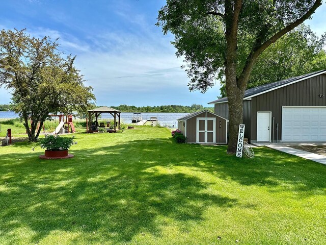46350 Cambridge Dr, Stanchfield, MN 55080 - view of grassy yard featuring a gazebo, a water view, a garage, and a playground