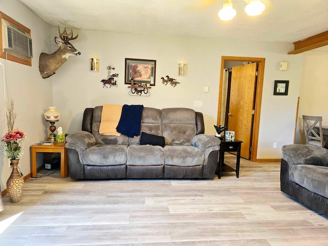 living room featuring an AC wall unit, light hardwood / wood-style flooring, and a textured ceiling