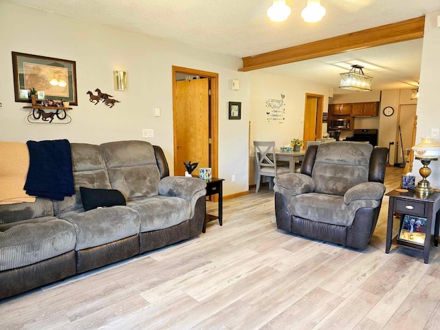 living room featuring beam ceiling, a textured ceiling, and light hardwood / wood-style flooring