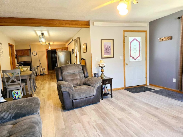 living room with beam ceiling, a textured ceiling, and light hardwood / wood-style flooring