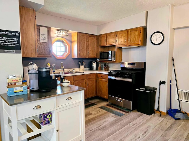 kitchen featuring appliances with stainless steel finishes, light wood-type flooring, a textured ceiling, and sink