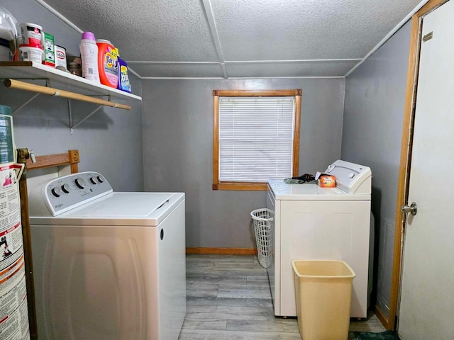 laundry area with washer and dryer, a textured ceiling, and light hardwood / wood-style floors