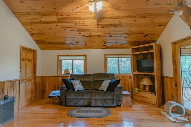 living room with wood walls, wood ceiling, vaulted ceiling, light hardwood / wood-style floors, and ceiling fan