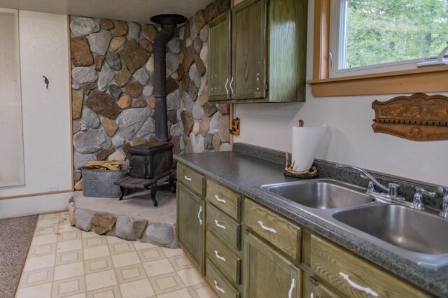 kitchen with green cabinets, sink, and a wood stove