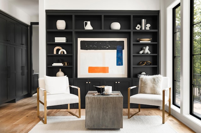 living area with built in shelves and light hardwood / wood-style flooring