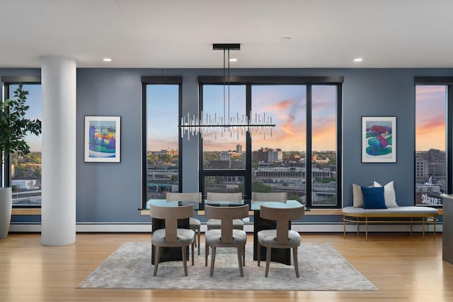 dining space with wood finished floors, recessed lighting, a city view, and a baseboard heating unit