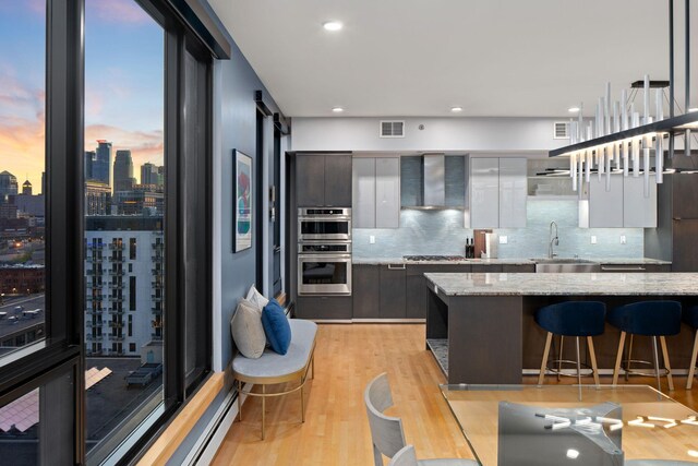 1240 2nd St Unit 1201, Minneapolis, MN 55415 - kitchen featuring wall chimney exhaust hood, modern cabinets, light wood finished floors, a breakfast bar area, and recessed lighting