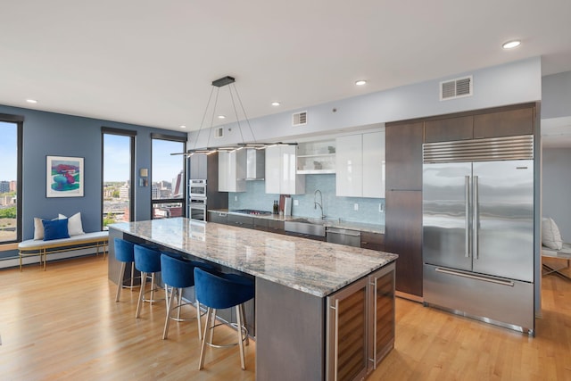 1240 2nd St Unit 1201, Minneapolis, MN 55415 - kitchen with appliances with stainless steel finishes, a breakfast bar area, light wood finished floors, a kitchen island, and recessed lighting