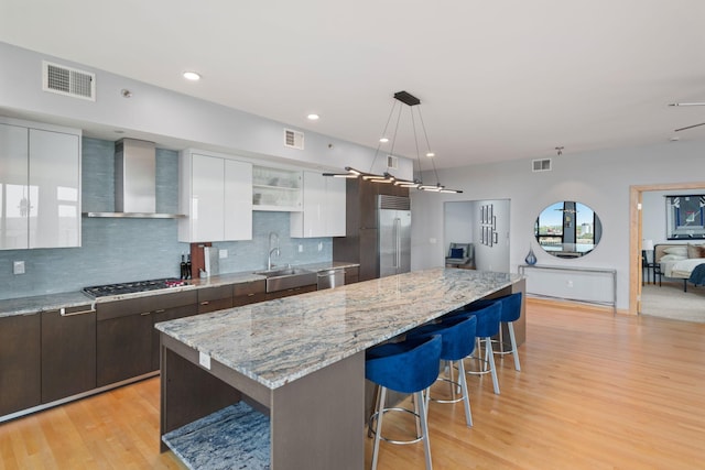 1240 2nd St Unit 1201, Minneapolis, MN 55415 - kitchen with wall chimney exhaust hood, modern cabinets, appliances with stainless steel finishes, white cabinets, and a breakfast bar
