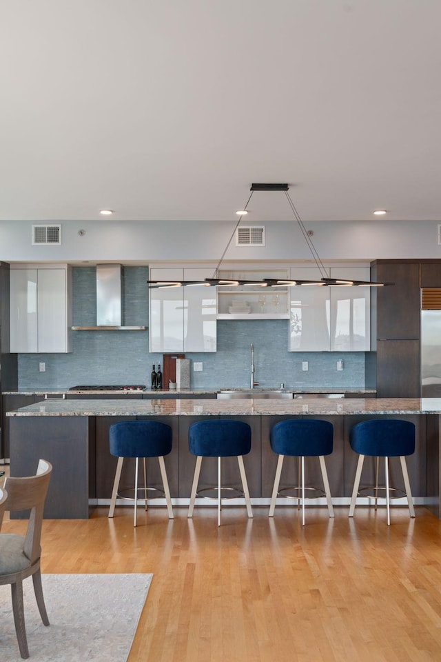 1240 2nd St Unit 1201, Minneapolis, MN 55415 - kitchen featuring wall chimney range hood, modern cabinets, light wood-style floors, decorative backsplash, and recessed lighting