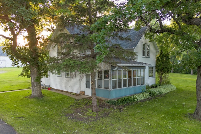 view of side of property with a sunroom and a lawn