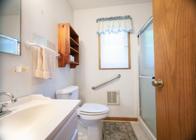 bathroom featuring vanity, toilet, plenty of natural light, and a shower with shower door