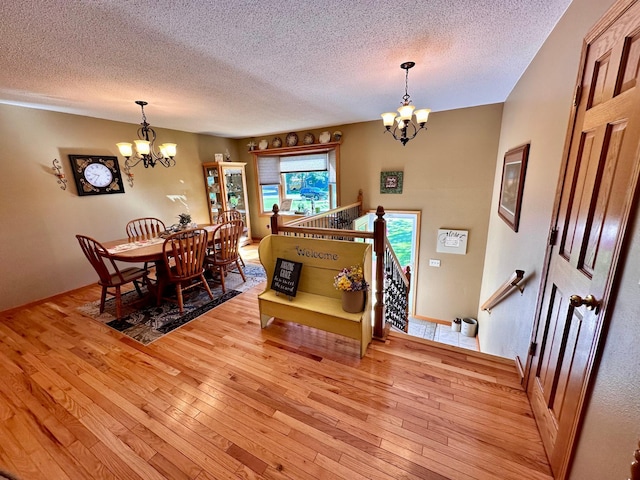 dining space featuring a notable chandelier, light hardwood / wood-style flooring, and a textured ceiling