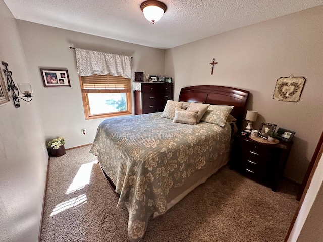 bedroom featuring a textured ceiling and dark colored carpet