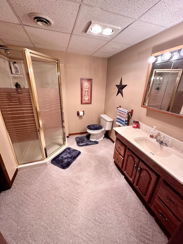 bathroom with a drop ceiling, vanity, and a shower with door