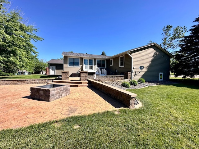 back of house featuring a yard, a fire pit, and a patio area