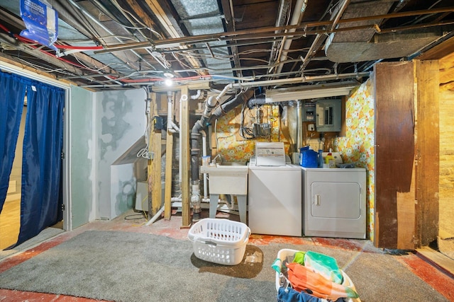 basement featuring electric panel, washer and dryer, and sink