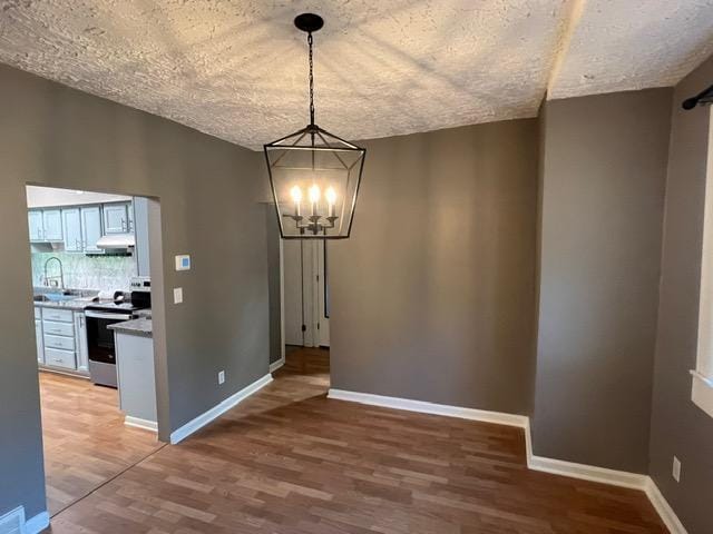 unfurnished dining area with a notable chandelier, sink, and light hardwood / wood-style floors