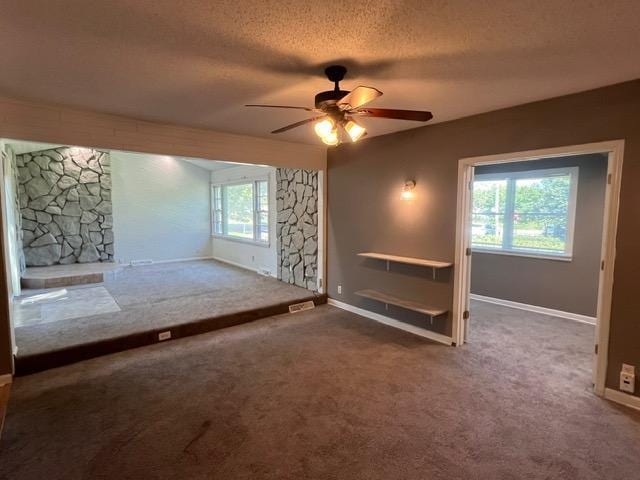 carpeted empty room with a textured ceiling, ceiling fan, and a wealth of natural light