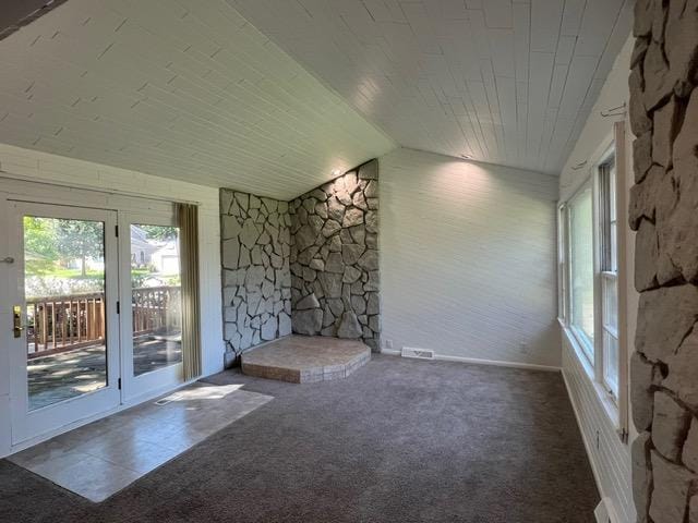 carpeted empty room featuring vaulted ceiling