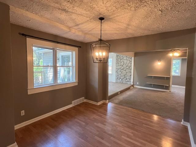 unfurnished dining area with a textured ceiling, carpet flooring, and a chandelier