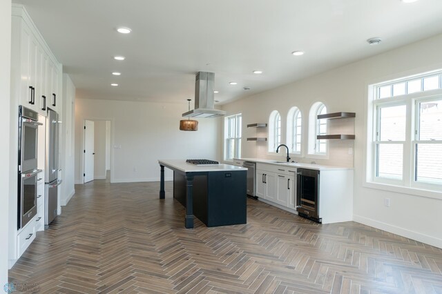 kitchen featuring white cabinetry, island exhaust hood, sink, a kitchen island, and wine cooler